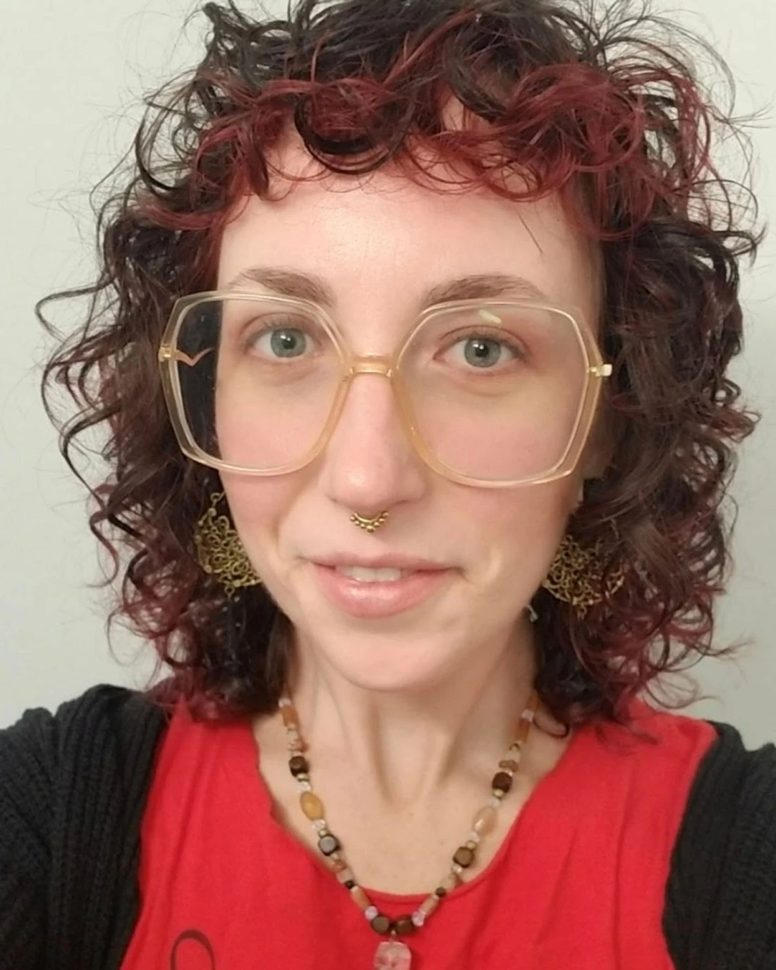 Rachel Scullion, Therapist at SEC LLC, smiling at the camera wearing big square glasses and a red shirt.