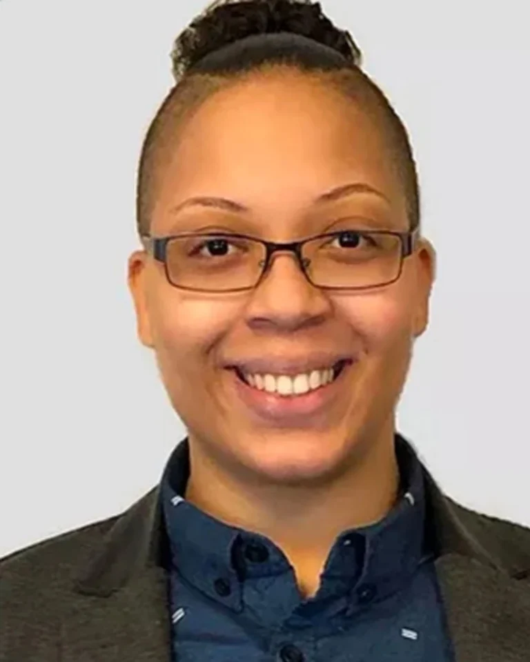 Ryan Townes, therapist at SEC LLC, smiling at the camera wearing rectangular thin framed glasses and a suit jacket.